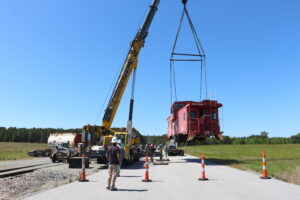 Historic Caboose moving on a crane to a flatbed truck